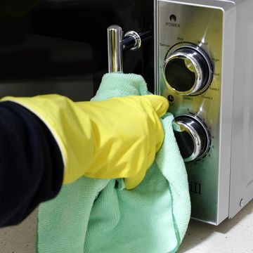close up of hand with rubber glove cleaning microwaves